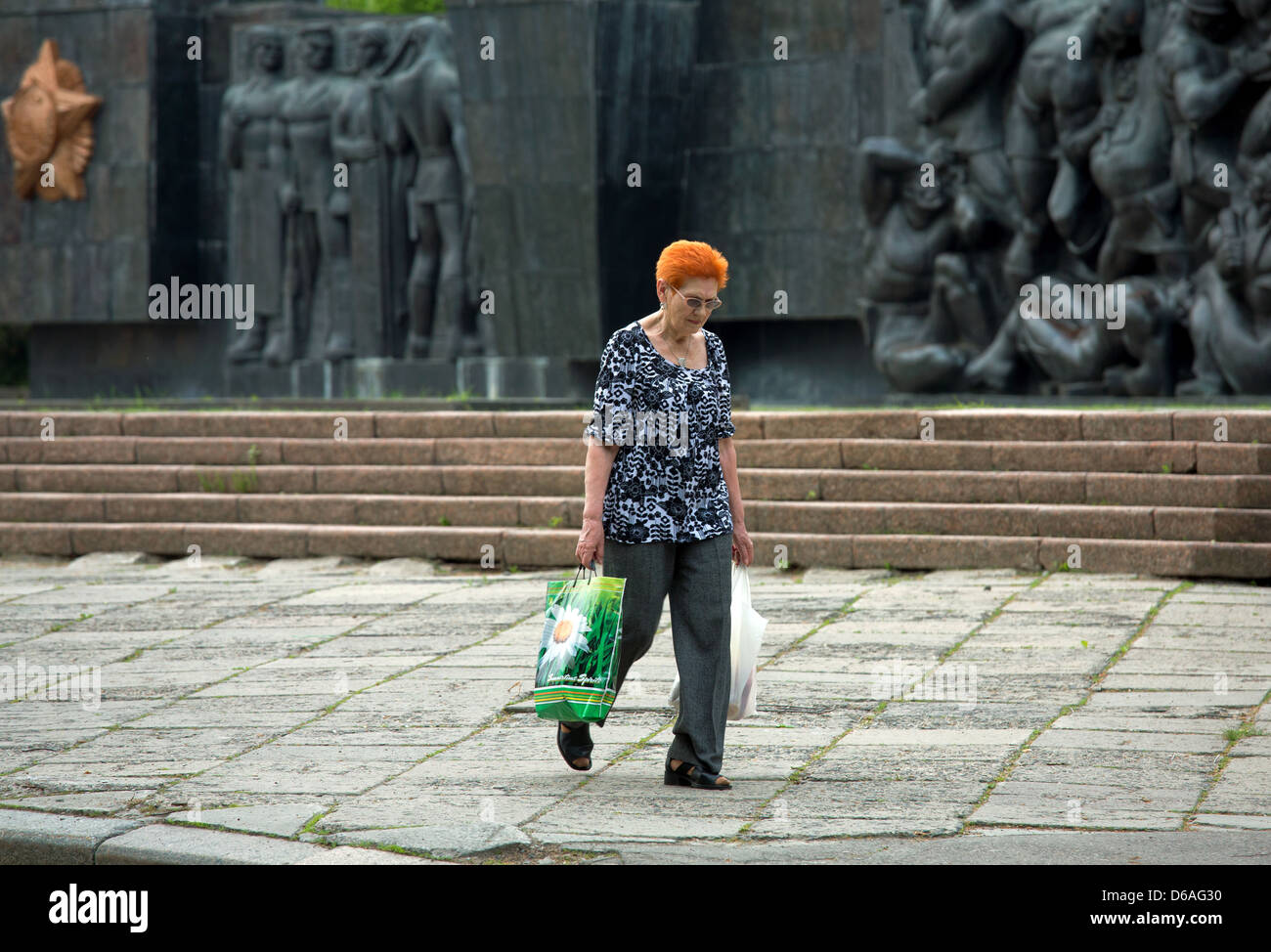 Lviv, Ucraina, donna con Einkaufstueten davanti al monumento di epoca sovietica Foto Stock