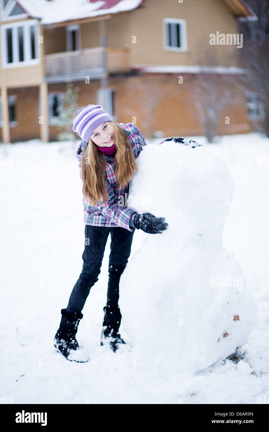Bambino ragazza rendendo pupazzo di neve all'aperto davanti a casa Foto Stock