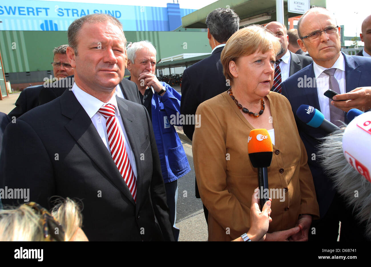 Il cancelliere tedesco Angela Merkel, Premier di Meclemburgo-pomerania Erwin Sellering (R) e Manager di P+S-Werften in Stralsund e Wolgast Ruediger Fuchs (L) dare una dichiarazione all'ingresso del cantiere Volksweft a Stralsund, Germania, 21 agosto 2012. Merkel ha preso parte a una riunione sul futuro della società di costruzione navale, dove i rappresentanti dei media non sono consentiti. Foto Stock