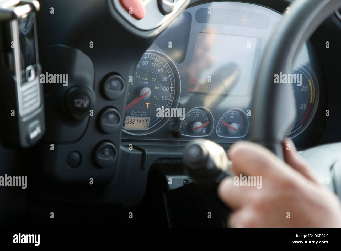 Interno cabina vista che mostra la mano trattenendo il volante del camion Iveco con la parte di cruscotto visibile Foto Stock