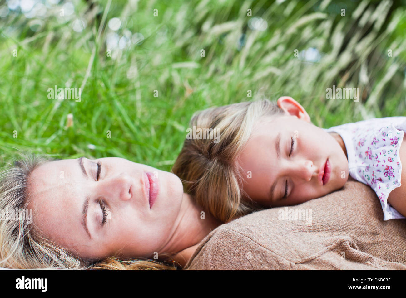 Madre e figlia napping in erba Foto Stock