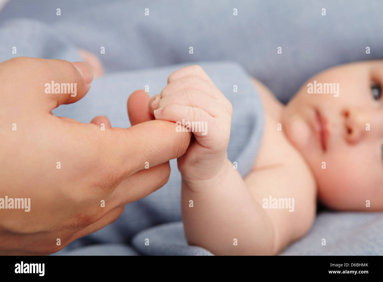 Baby boy holding madri dito nel letto Foto Stock