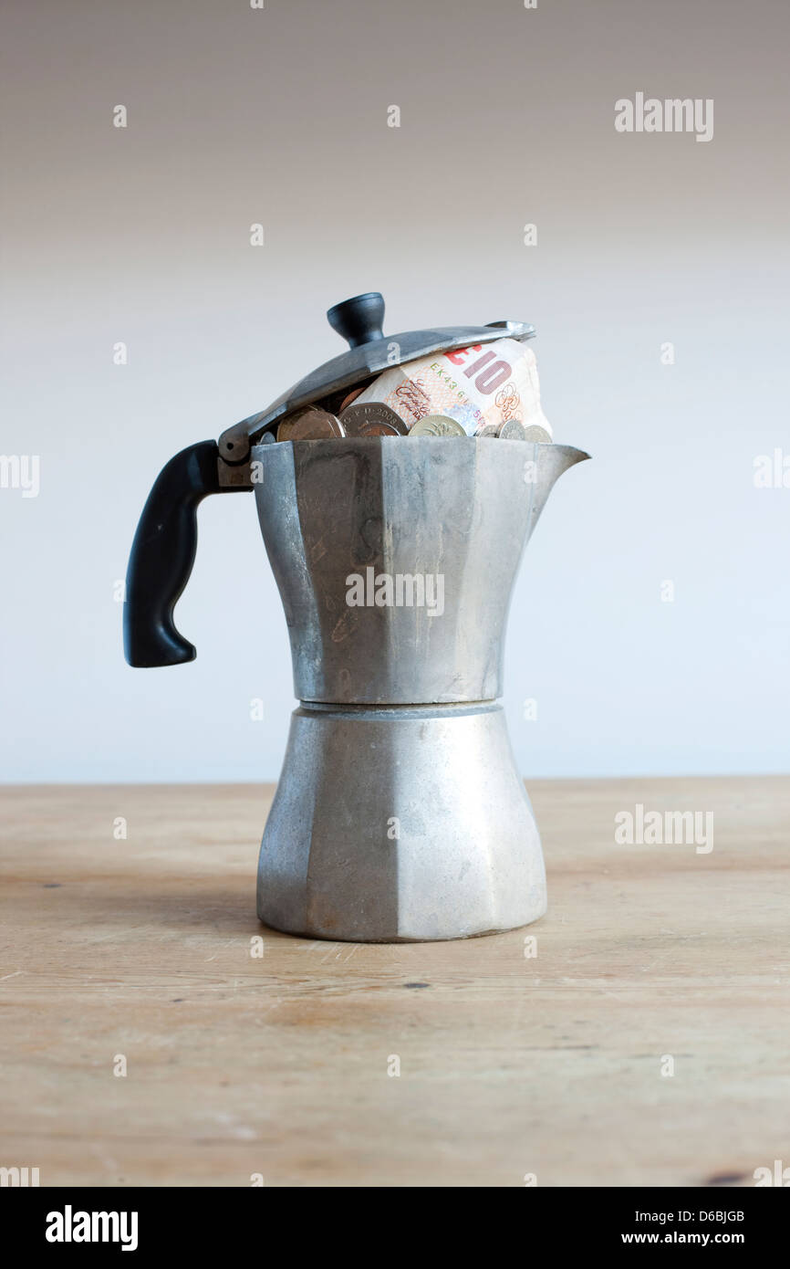 Caffettiera piena di soldi sulla scrivania Foto Stock