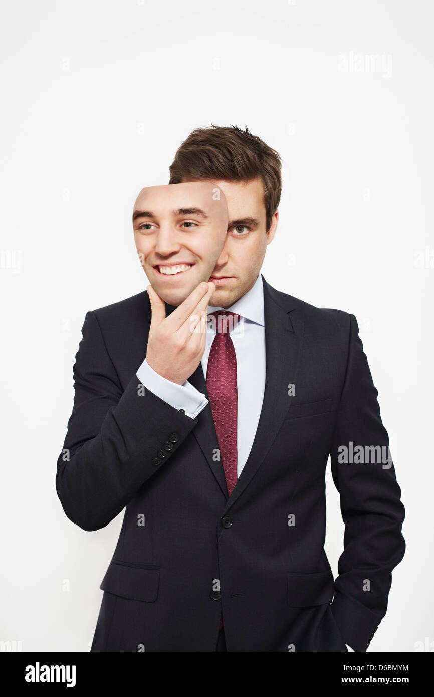 Imprenditore tenendo la maschera sul viso Foto Stock