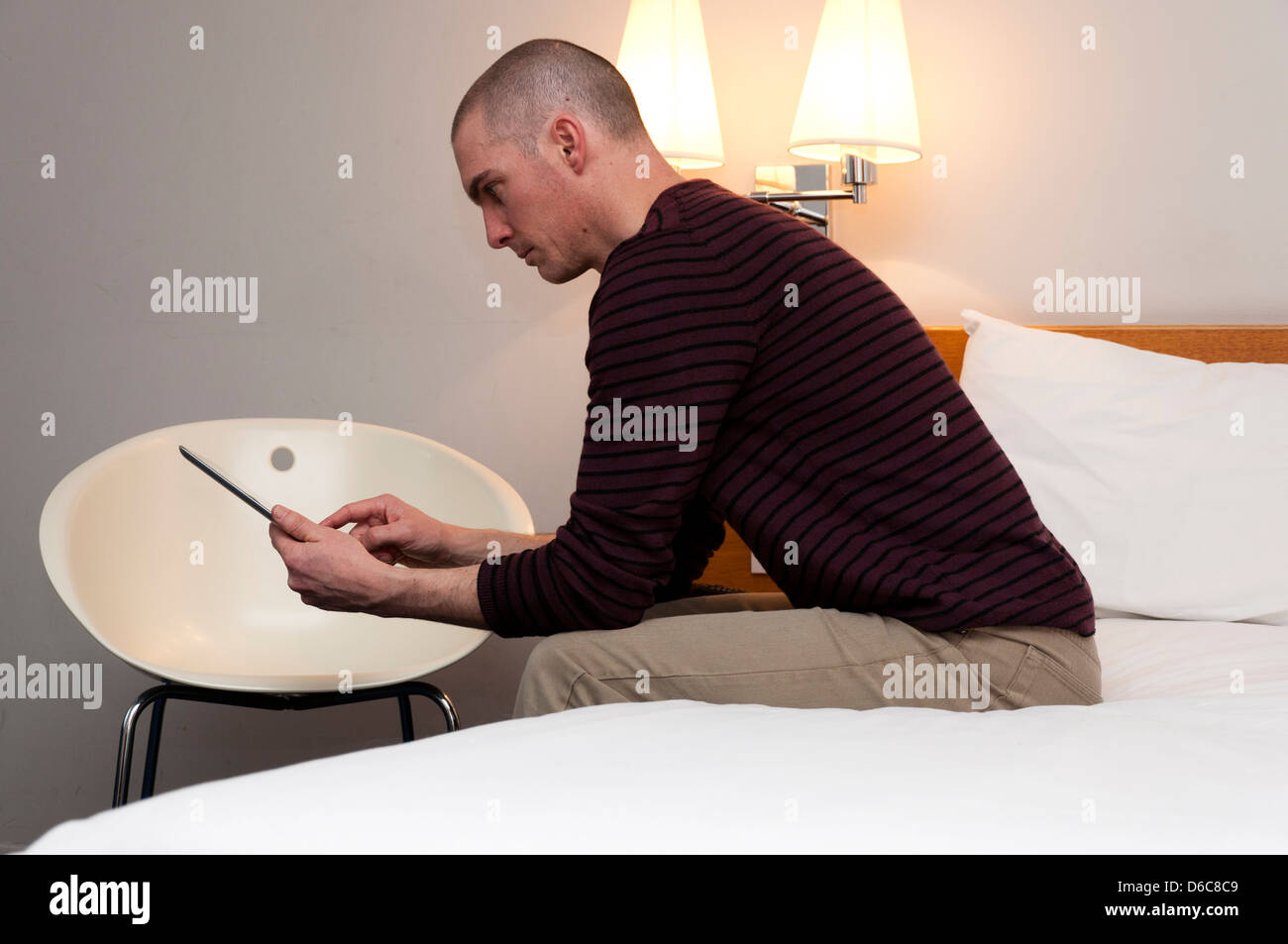 Uomo che utilizza computer tablet in camera d'albergo. Foto Stock