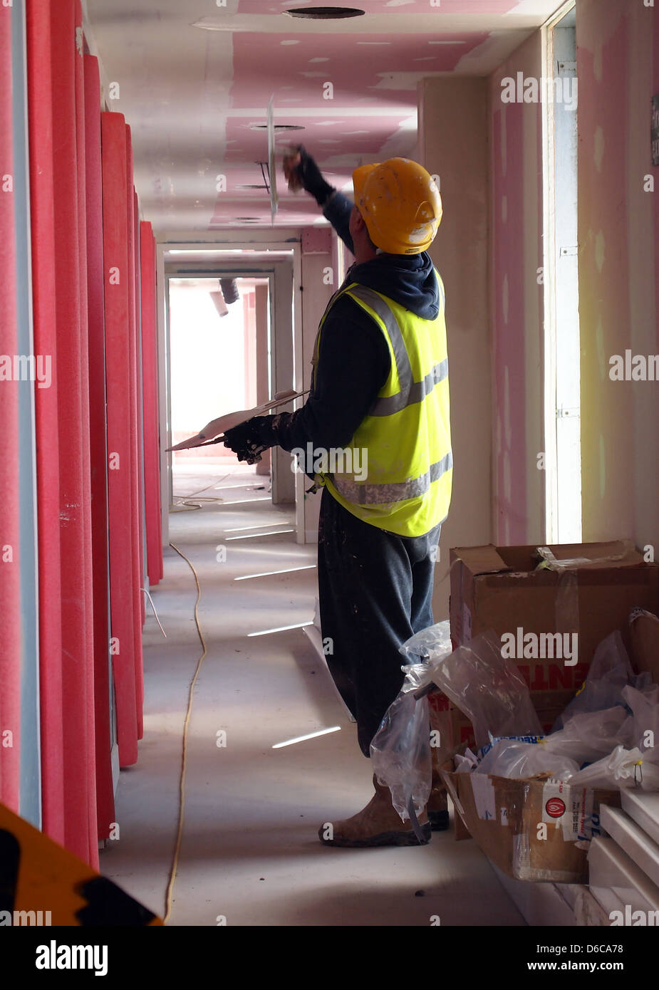 Un uomo su un sito in costruzione intonacare il soffitto di un corridoio di hotel. Aprile 2013 Foto Stock