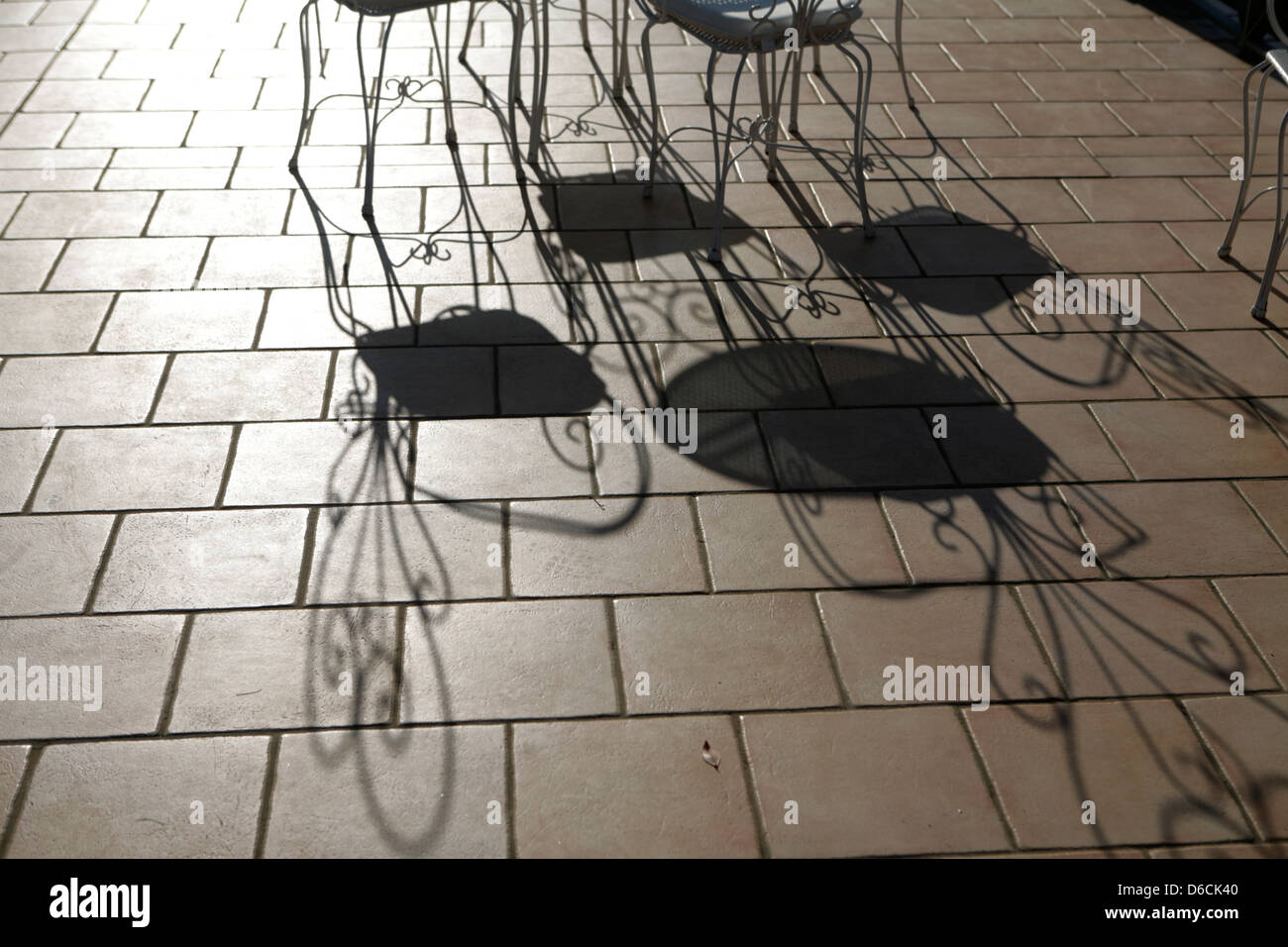 Lunghe ombre su un marrone pavimento piastrellato da ornati in sedie Foto Stock