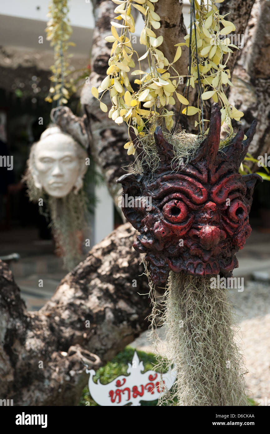 Chiang Rai, Thailandia, la testa di una figura demoniaca con fiori Foto Stock