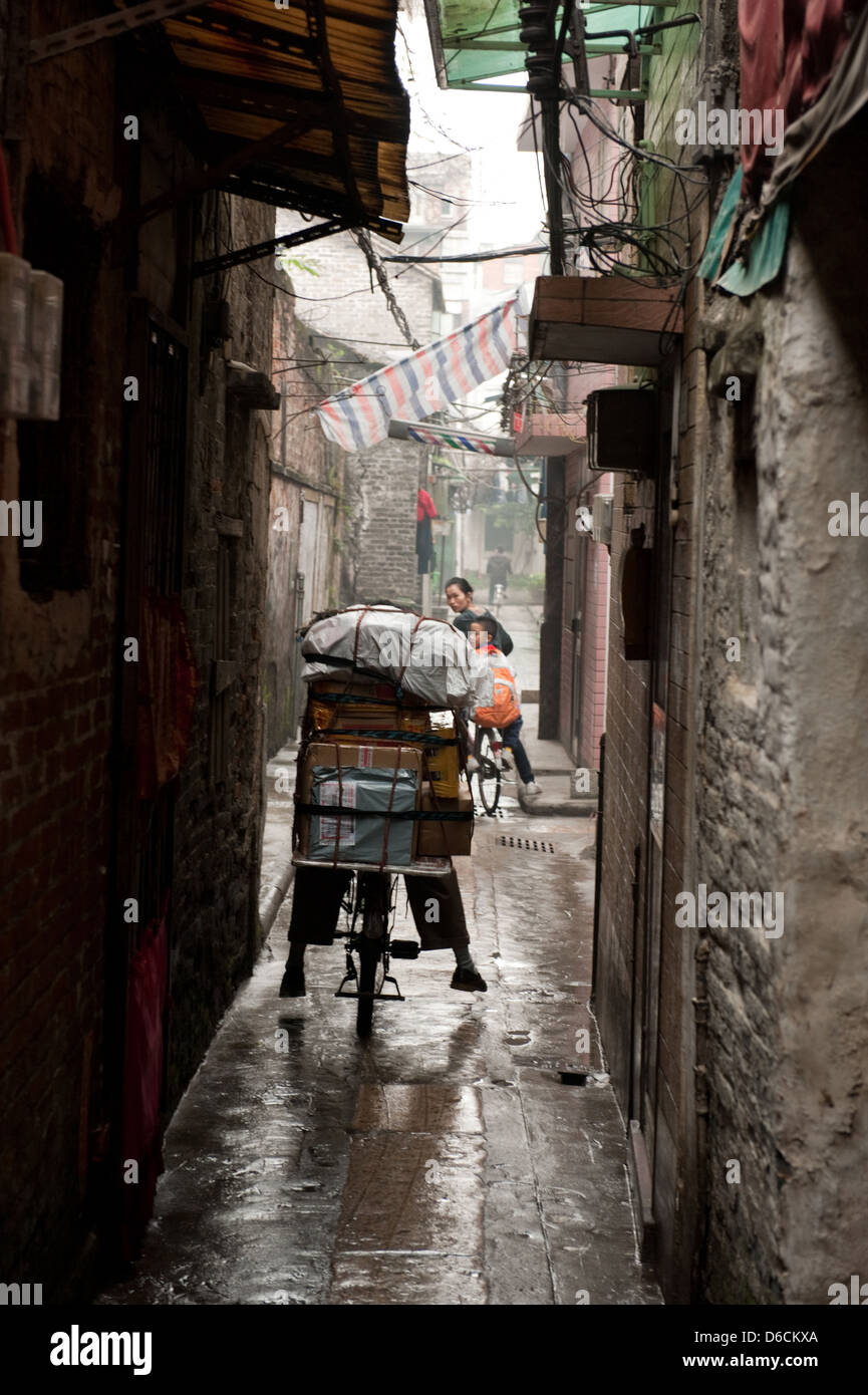 Guangzhou, Cina, i ciclisti con un pieno carico in uno stretto vicolo Foto Stock