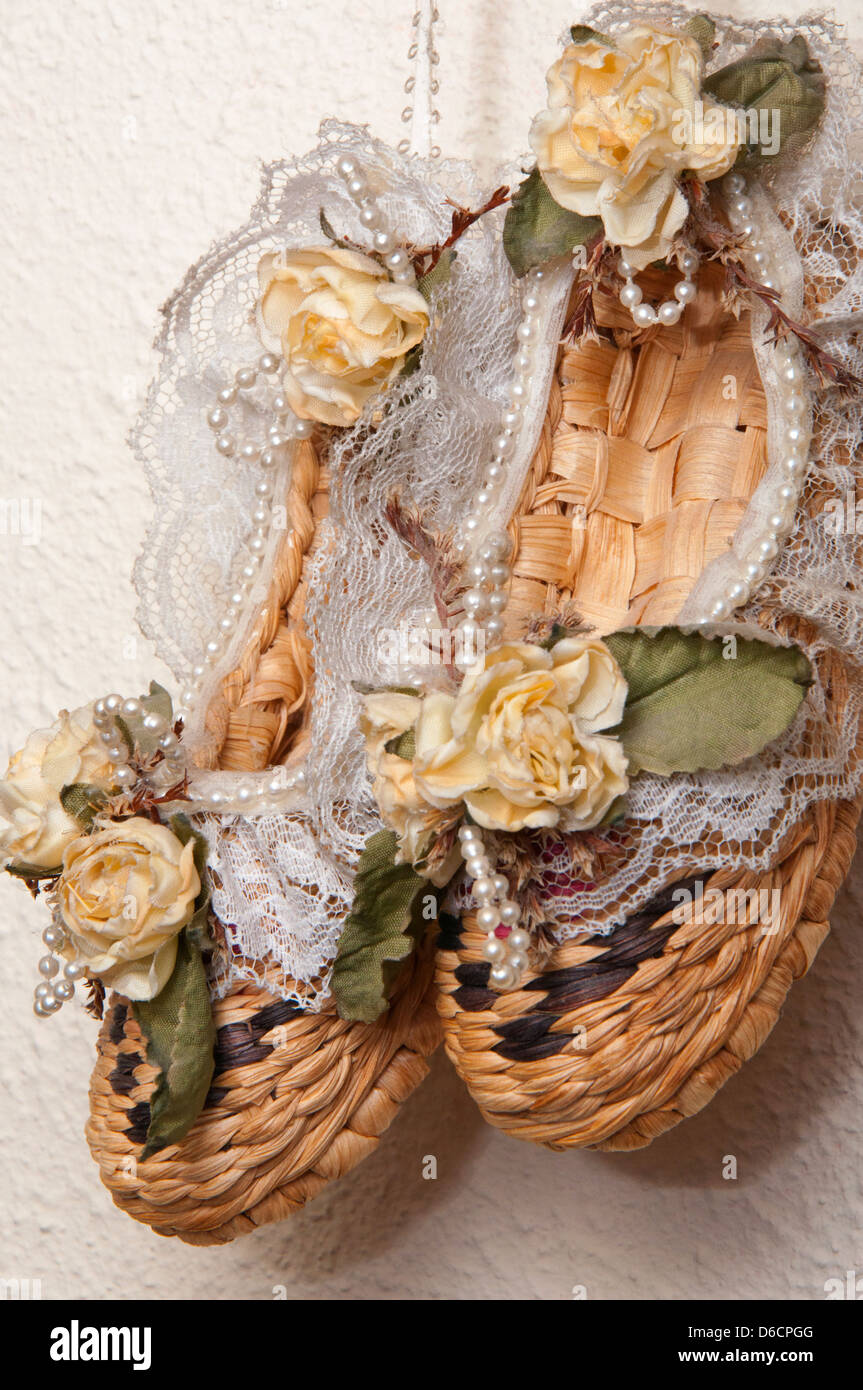 Scarpe di vimini come decorazione, perle, pizzo,fiori artificiali, montaggio a parete, Foto Stock