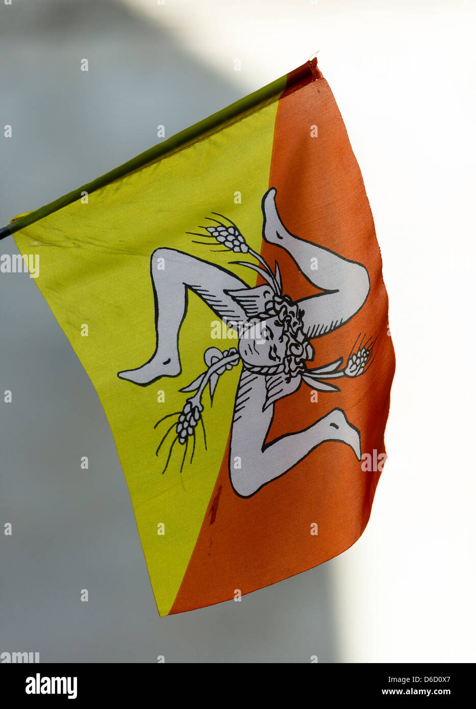 La bandiera siciliana, comprendente una gorgone alata la testa e covoni di grano nella parte anteriore di un triskelion su un arancio e giallo terra. Foto Stock