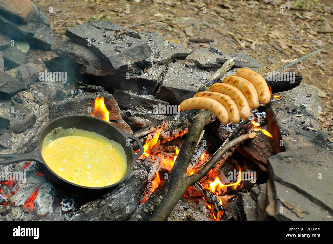 Uova fritte sul fuoco a ferro pan fritto con salsicce alla griglia su spiedino Foto Stock