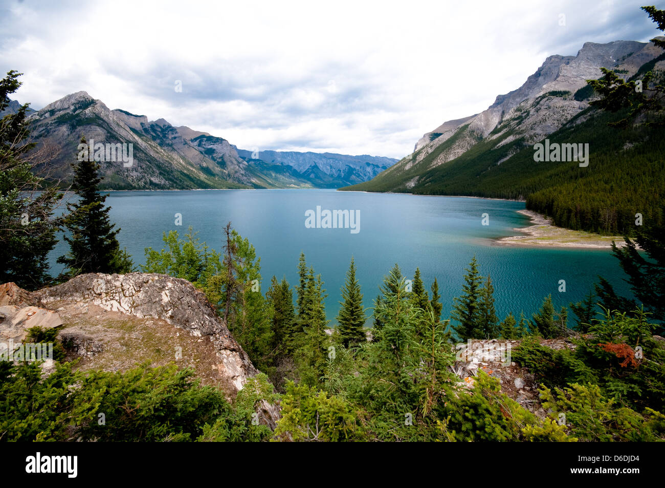 Eccellente immagine del Lago Minnewanka, Alberta, Canada. L'acqua turchese con un primo piano boscoso. Il cielo è nuvoloso. Foto Stock