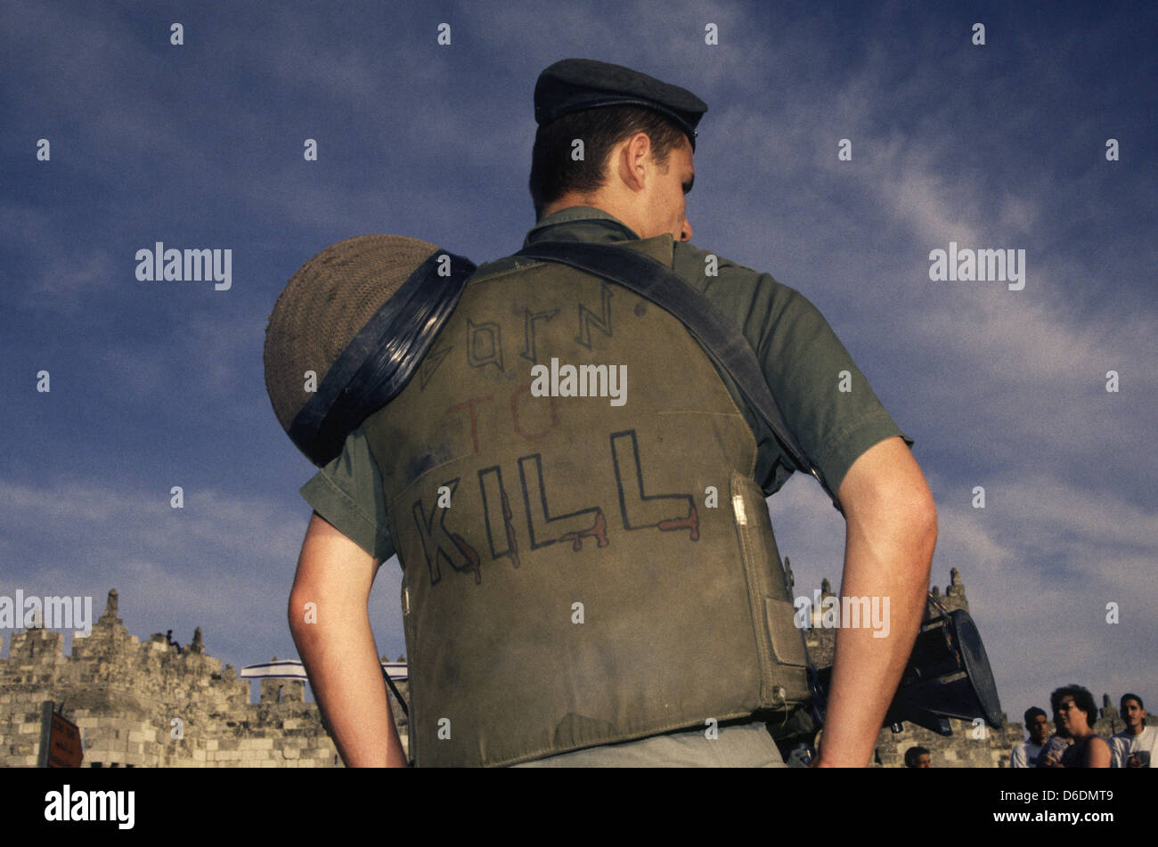 Un soldato israeliano che indossa un cappuccio di Flak Jacket con scritto sul retro le parole "Nato per uccidere' a Gerusalemme Est, Israele Foto Stock