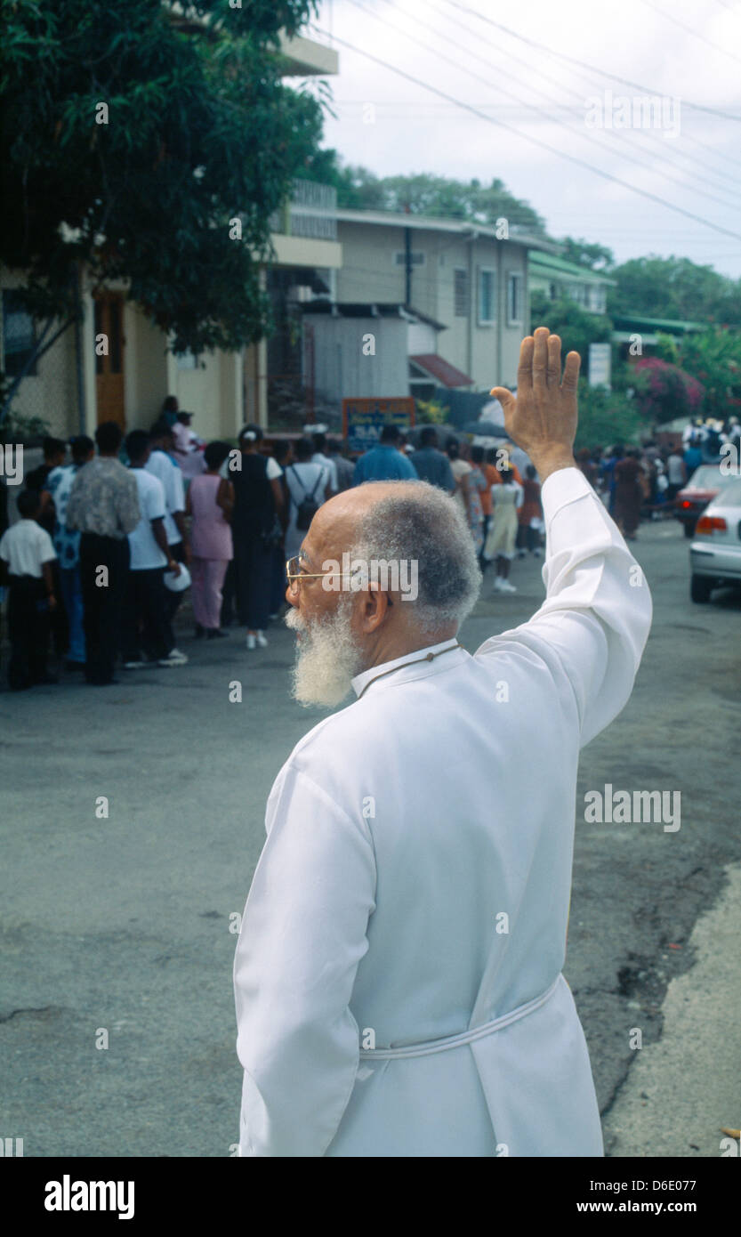 Scarborough Tobago sacerdote mantenendo la mano per arrestare il traffico durante la processione del Corpus Domini Foto Stock