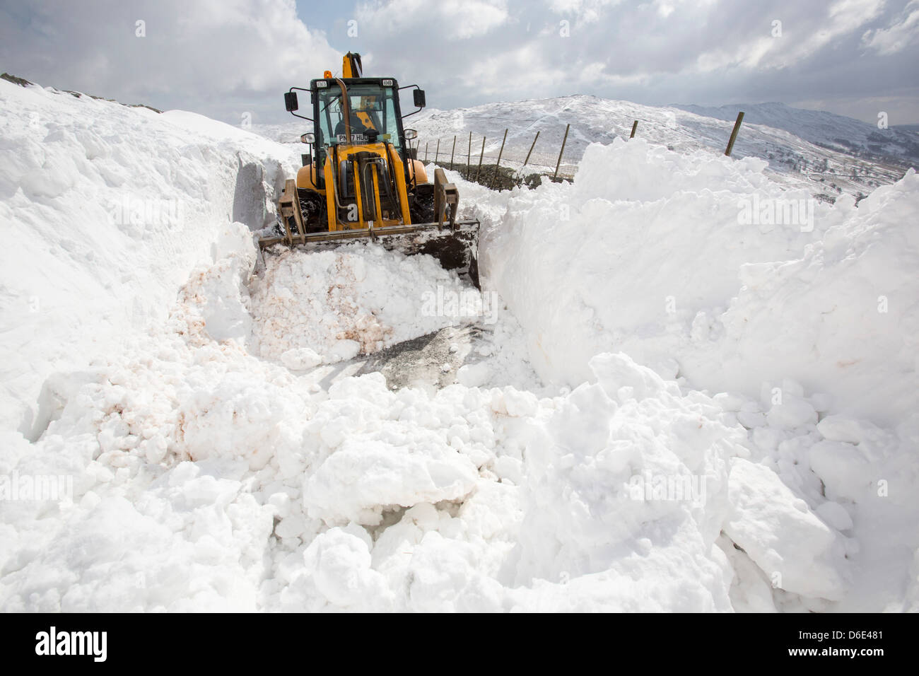 Un JCB tenta di cancellare un modo attraverso la massiccia neve si sposta bloccando il Kirkstone Pass Foto Stock