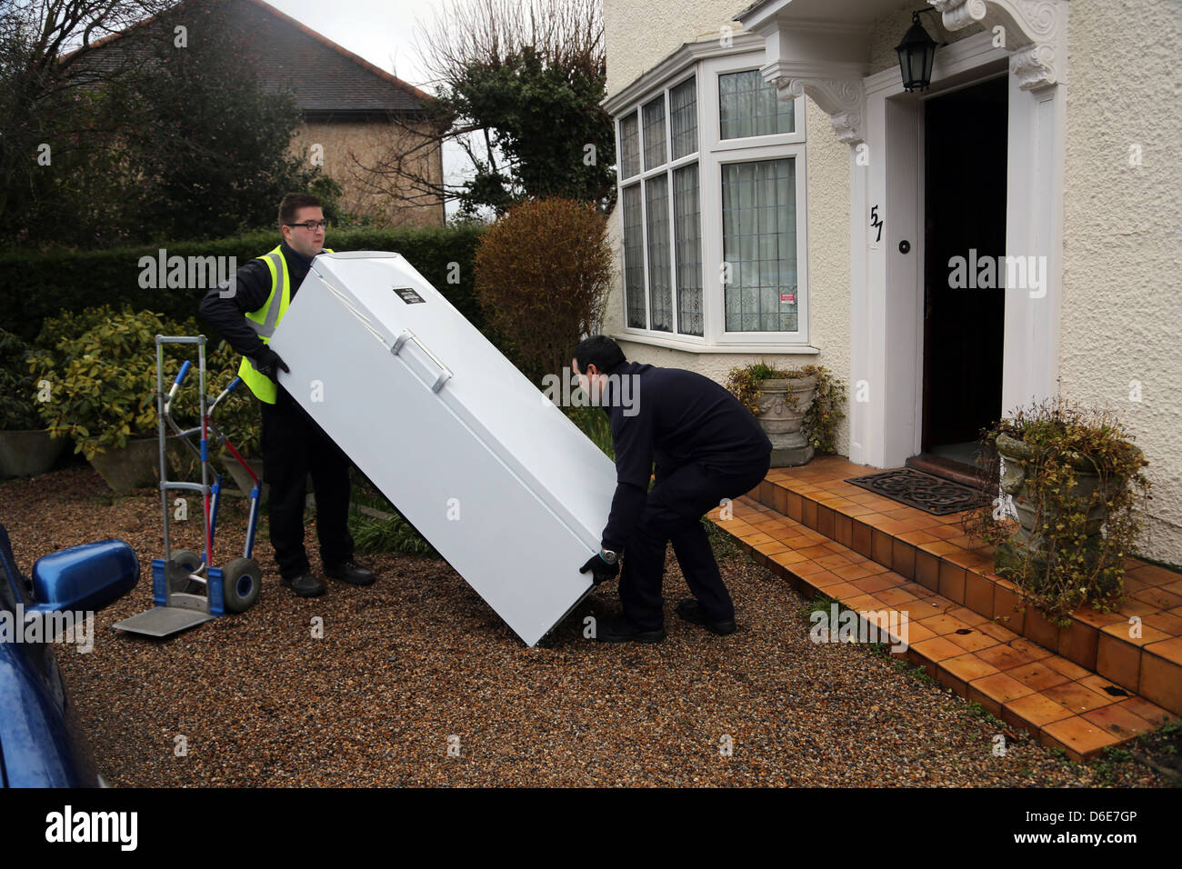 Fornire un congelatore uomini di sollevamento di un congelatore pesanti in un home Inghilterra Foto Stock