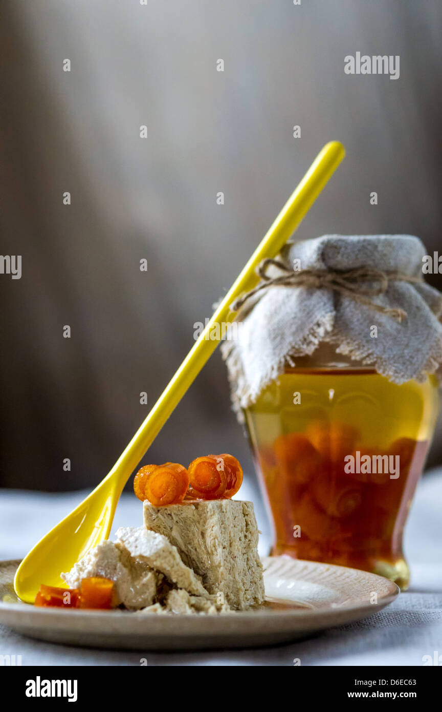 Vaso di vetro di marmellata di arancio, giallo cucchiaio e dolce halva ritorto con bucce di arancia su una piastra Foto Stock