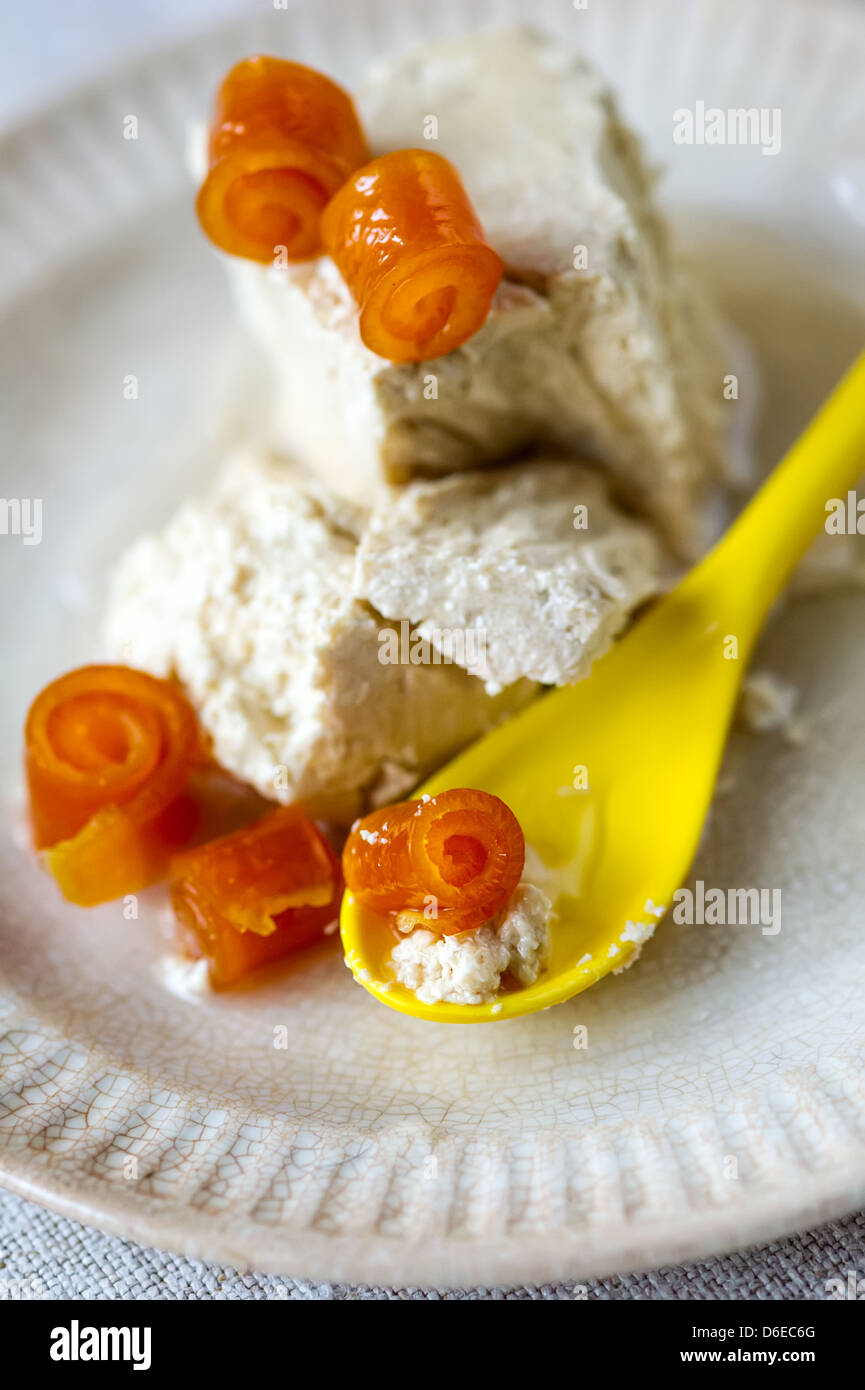 Il dolce halva ritorto con bucce di arancio e giallo cucchiaio su una piastra Foto Stock