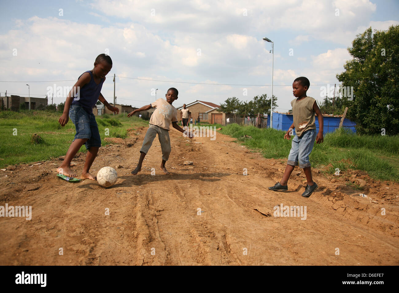 African ragazzi giocare a calcio per strada sterrata in un piccolo insediamento rurale Foto Stock