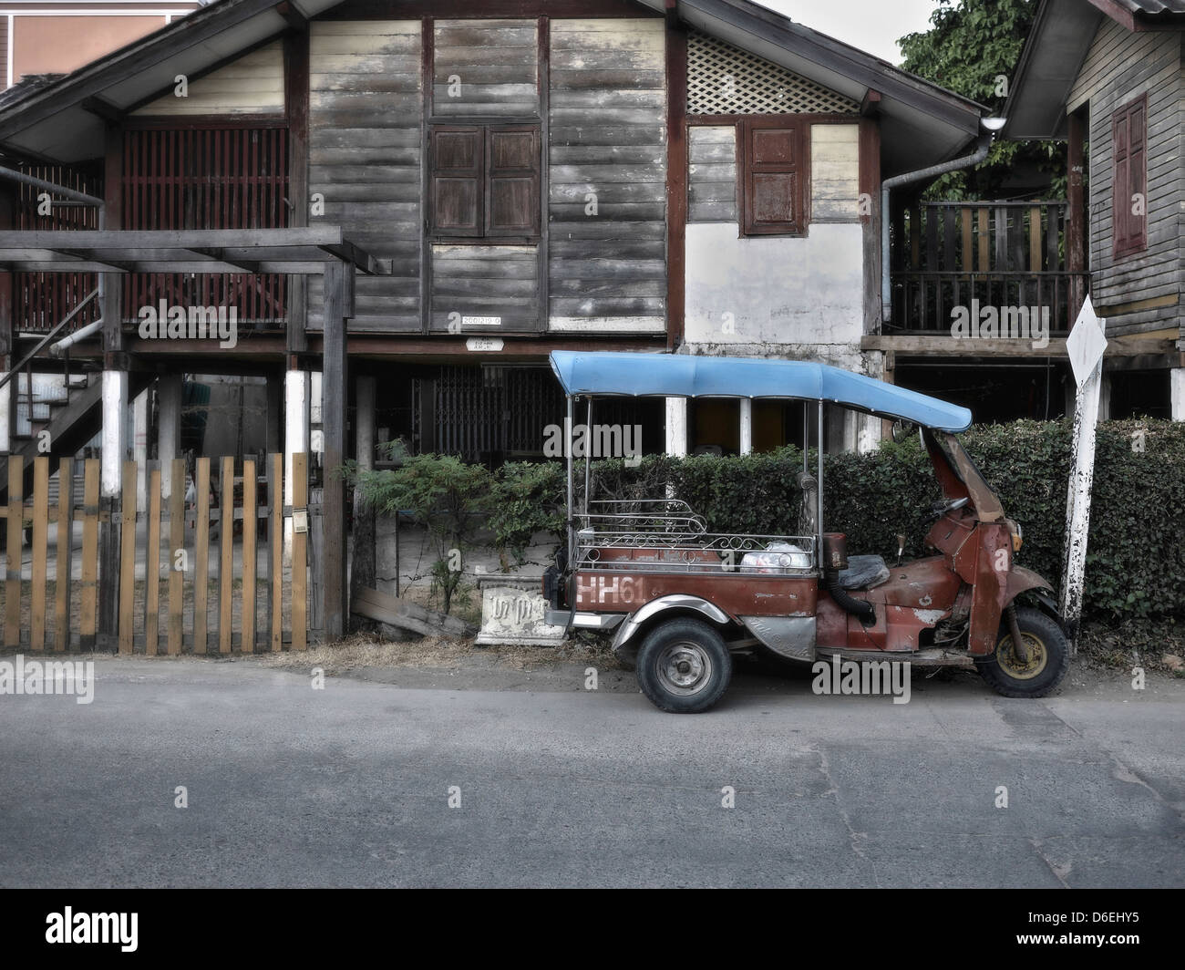 Vintage Thai Tuk Tuk parcheggiato al di fuori di un vecchio e tradizionale della Thailandia casa in legno. Thailandia Sudest Asiatico. Foto Stock