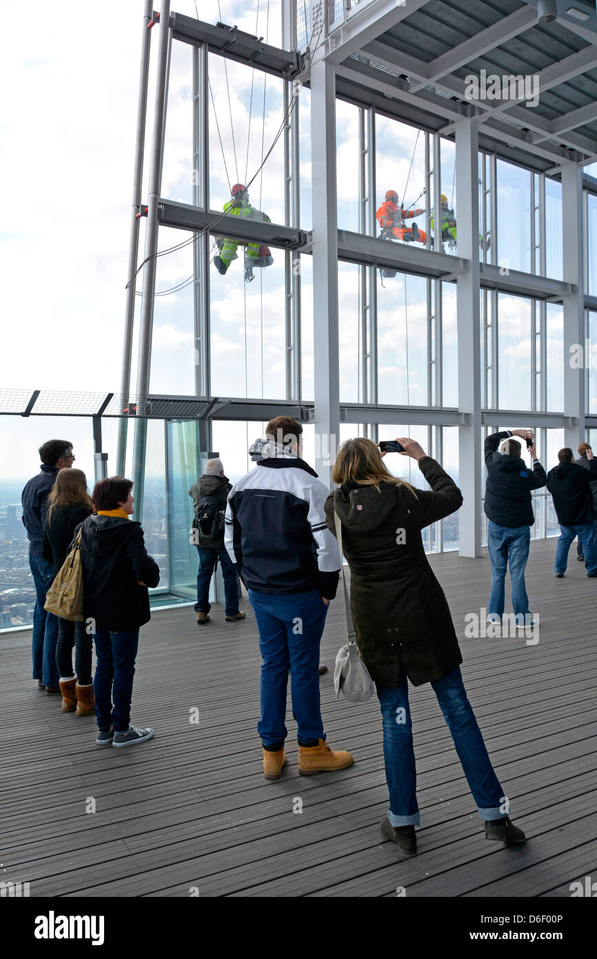I visitatori del Shard edificio galleria di visualizzazione a fotografare gli operai sulla faccia esterna di windows Foto Stock