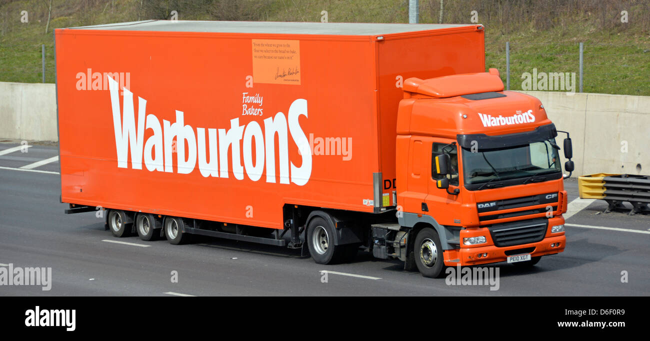 I dettagli aziendali della panetteria di proprietà della famiglia Warburtons pubblicizzati sul lato della catena di fornitura del pane camion e rimorchio che guida lungo l'autostrada M25 UK Foto Stock