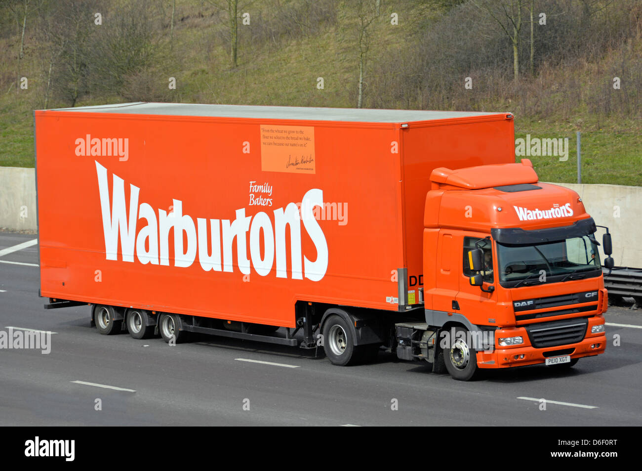 I dettagli aziendali della panetteria di proprietà della famiglia Warburtons pubblicizzati sul lato della catena di fornitura del pane camion e rimorchio che guida lungo l'autostrada M25 UK Foto Stock