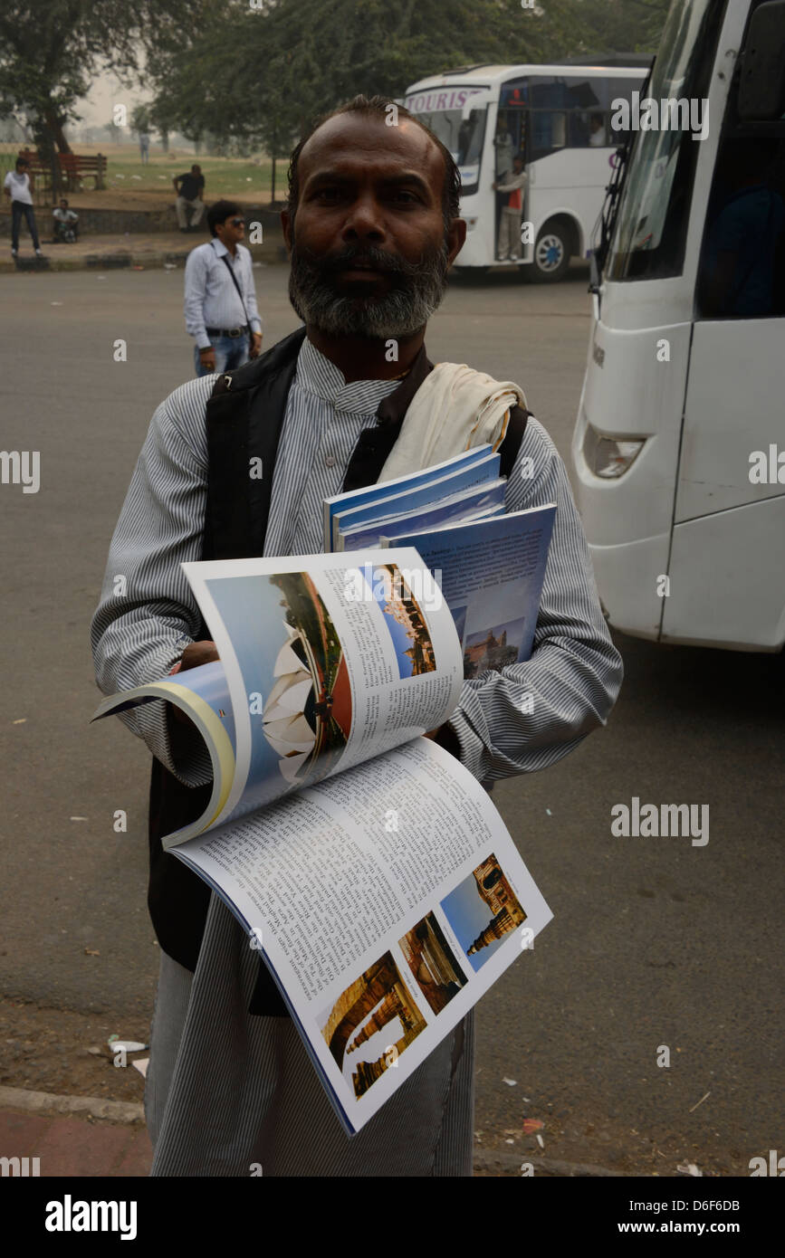 Un venditore ambulante che offre al turista souvenir libri sui monumenti di Delhi, India Foto Stock