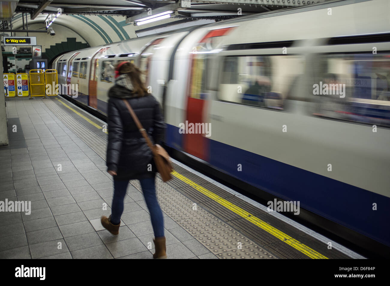Di " commuters " femmina passeggiate lungo una piattaforma su London Underground system come un treno parte. Foto Stock