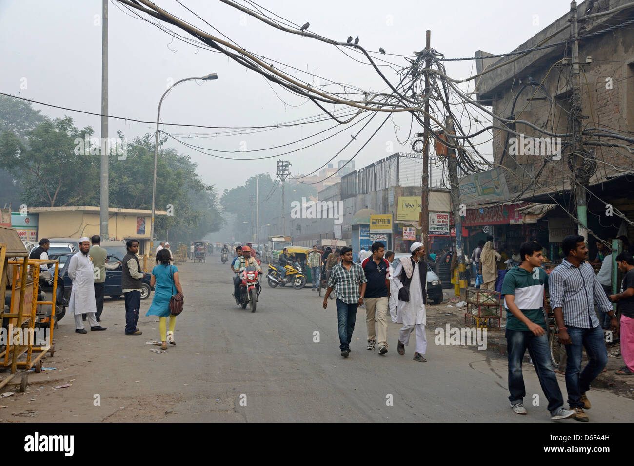 Una delle tante strade strette con edifici sbriciolati e cavi spessi nella Vecchia Delhi, India Foto Stock