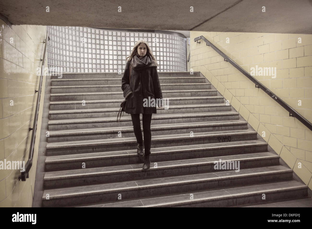 Donna pochi passi verso il basso in corrispondenza di un ingresso della metropolitana a Berlino, Germania Foto Stock