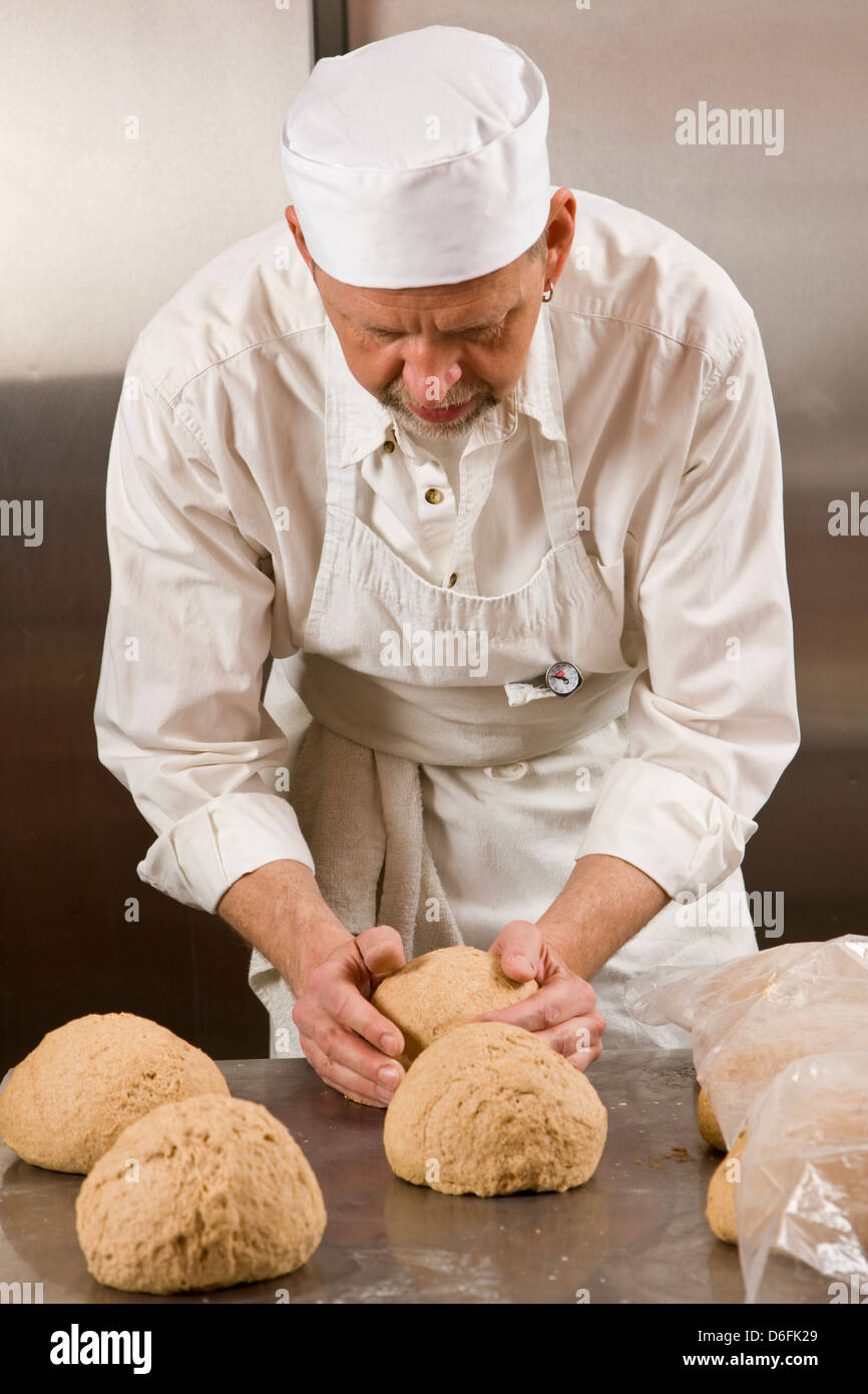 Cuoco professionista, preparare il pane fresco in un forno commerciale Foto Stock