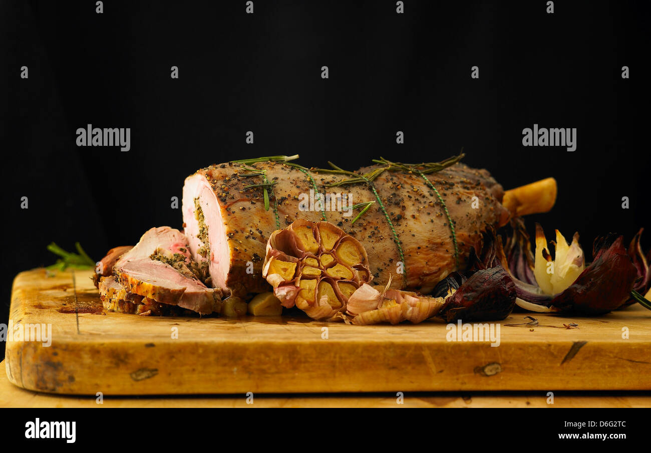 Fette di cosciotto di agnello farcito con aglio, rosmarino e cipolle arrosto Foto Stock