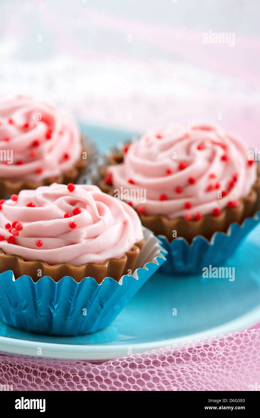 Spruzzi di colore rosso sul cupcake rosa Bonbons di cioccolato - assortimento di pasticceria romantico su shabby chic di sfondo Foto Stock
