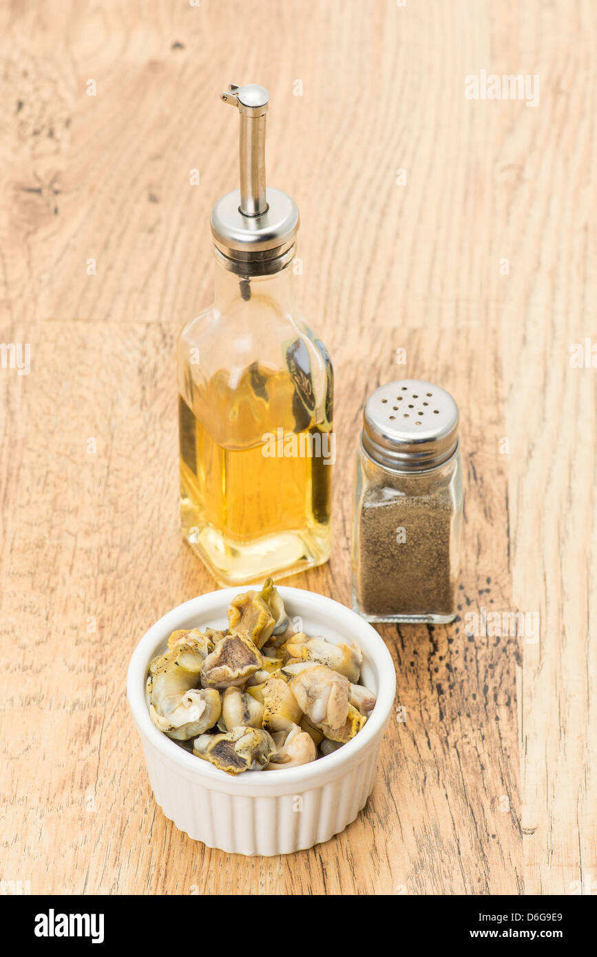 Una porzione di conchiglia fresche che sono pronti a mangiare con una bottiglia di aceto e una macinata di pepe. Foto Stock