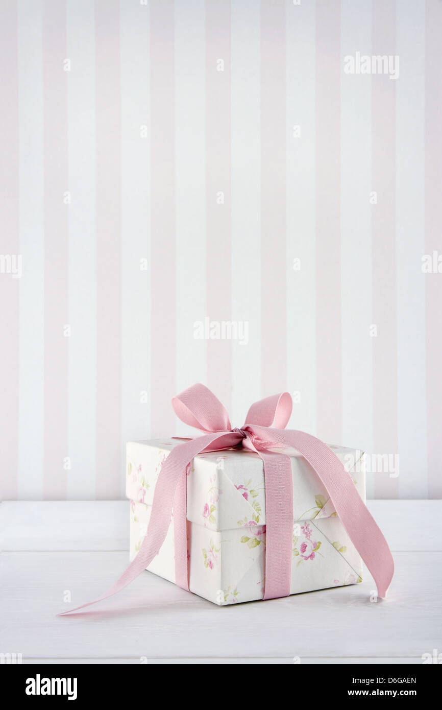 Motivo floreale confezione regalo legato con nastro rosa bianca su sfondo di legno con spazio di copia Foto Stock