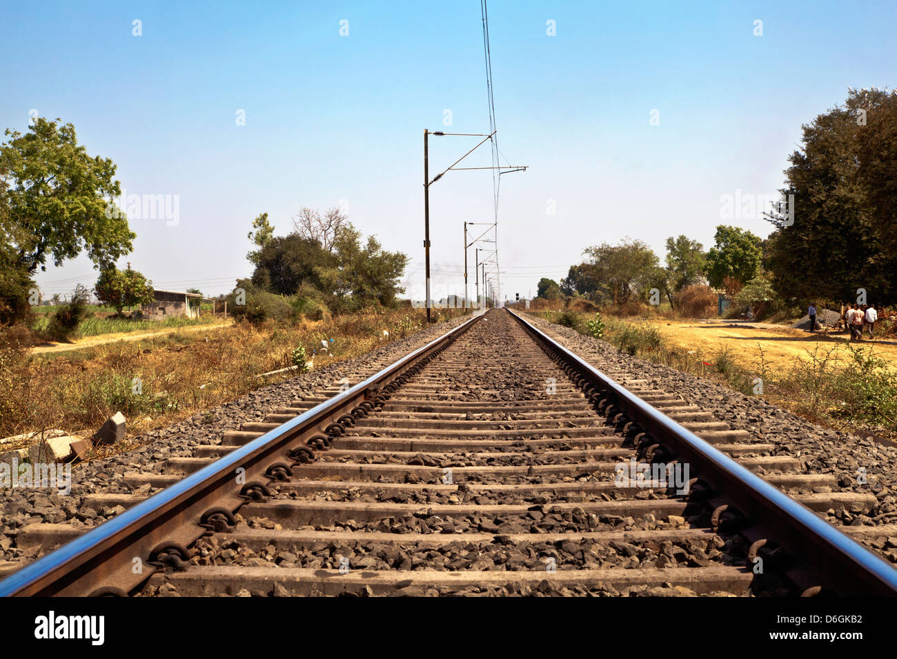 I binari della ferrovia in Indian taglio attraverso il paesaggio rurale lungo la periferia di o Gujarat village Foto Stock