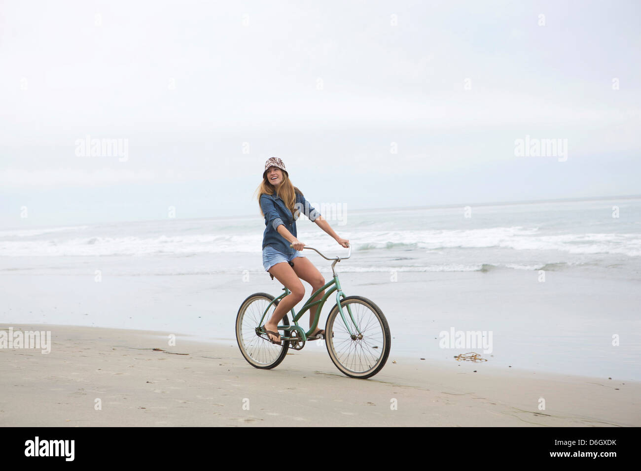 Donna Bicicletta Equitazione sulla spiaggia Foto Stock