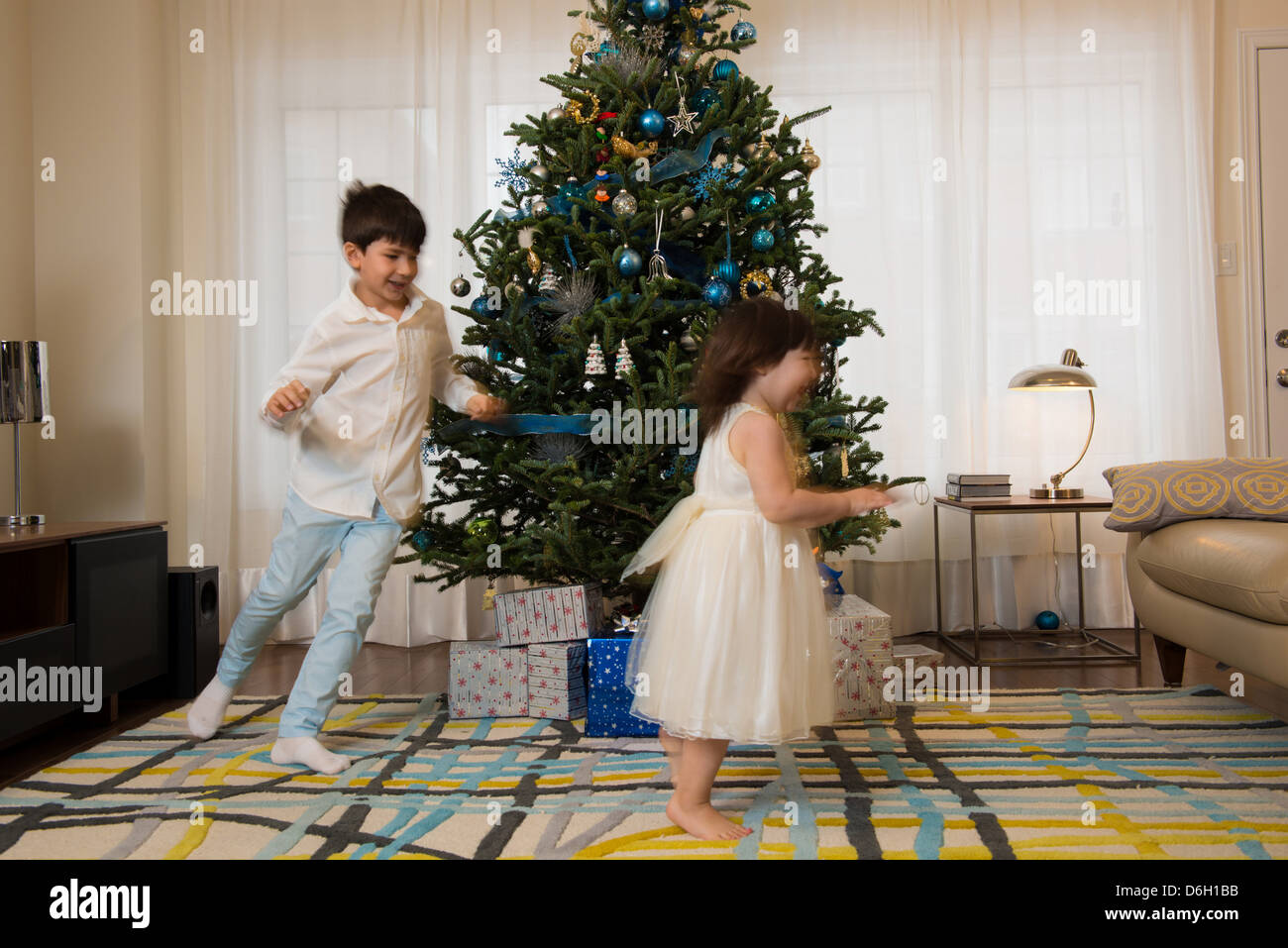 Bambini che giocano attorno ad albero di Natale Foto Stock