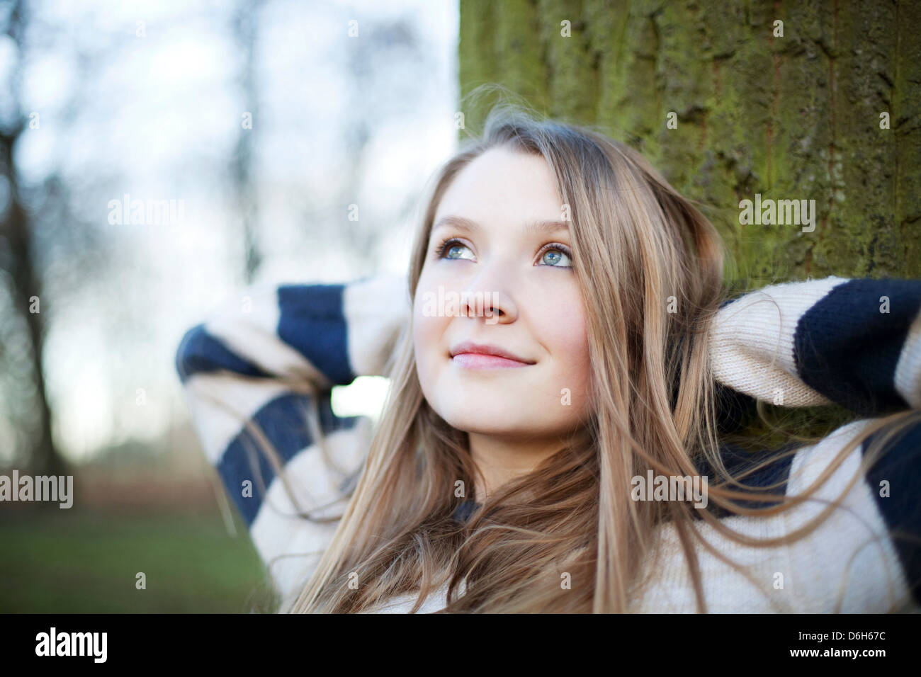 Donna seduta mediante una struttura ad albero all'aperto Foto Stock