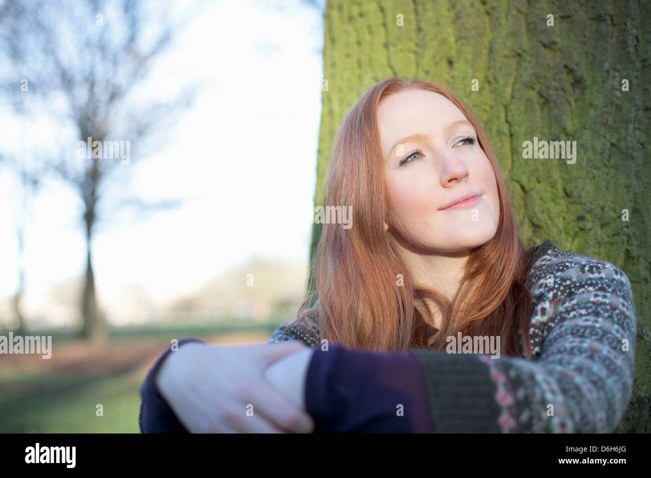 Donna seduta mediante una struttura ad albero all'aperto Foto Stock