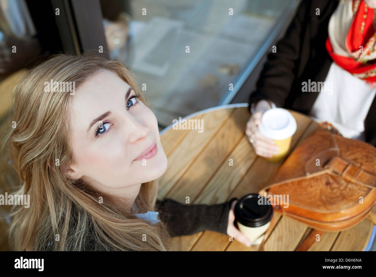 Donna sorridente al cafè sul marciapiede Foto Stock