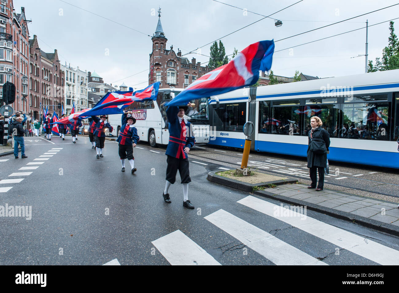 I membri delle Corporazioni artigiane sfilata in costume sventolando bandiere nel centro di Amsterdam. Foto Stock