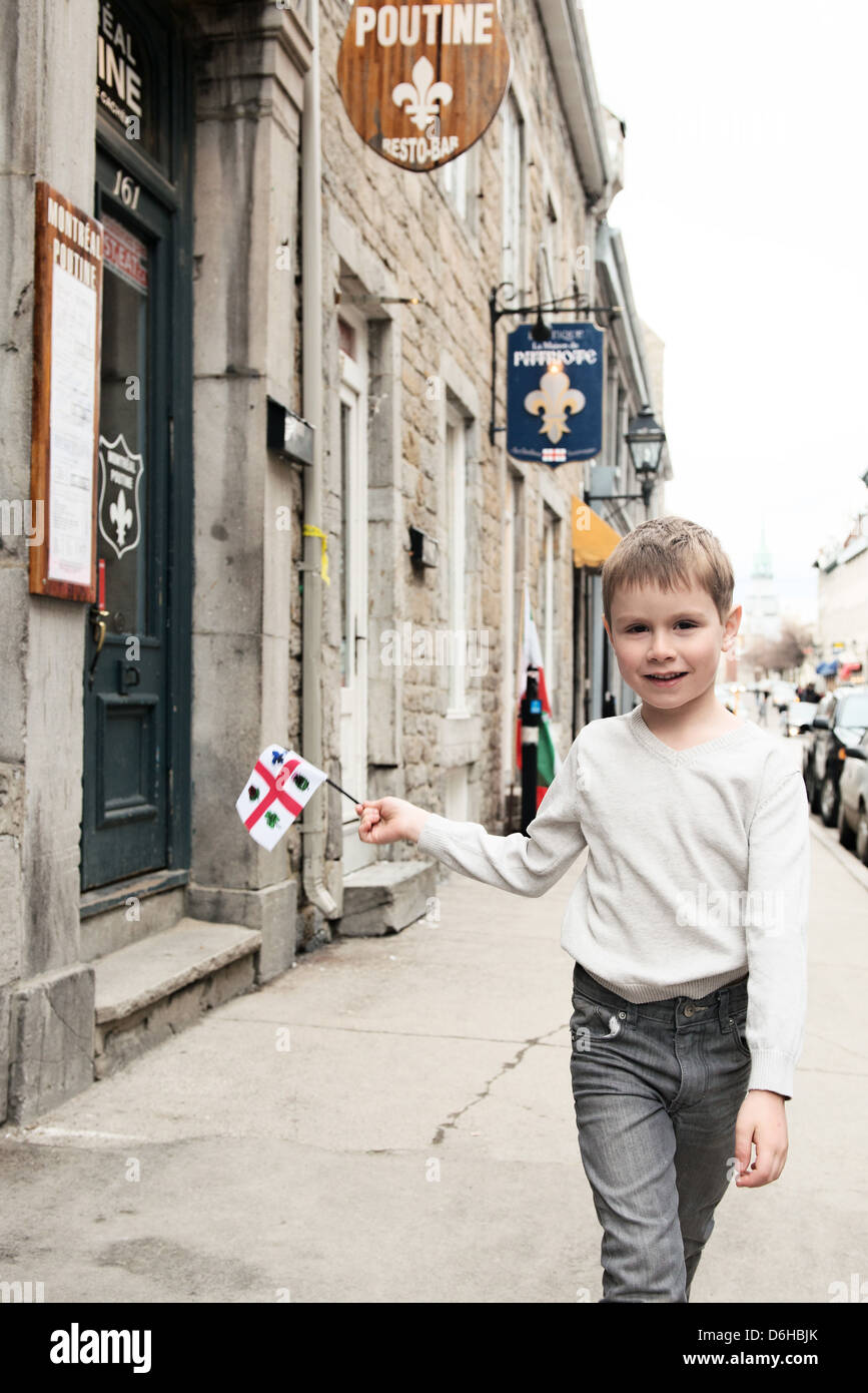 Ragazzo a piedi su Rue Saint Paul nella vecchia Montreal sventola una bandiera di Montreal Foto Stock
