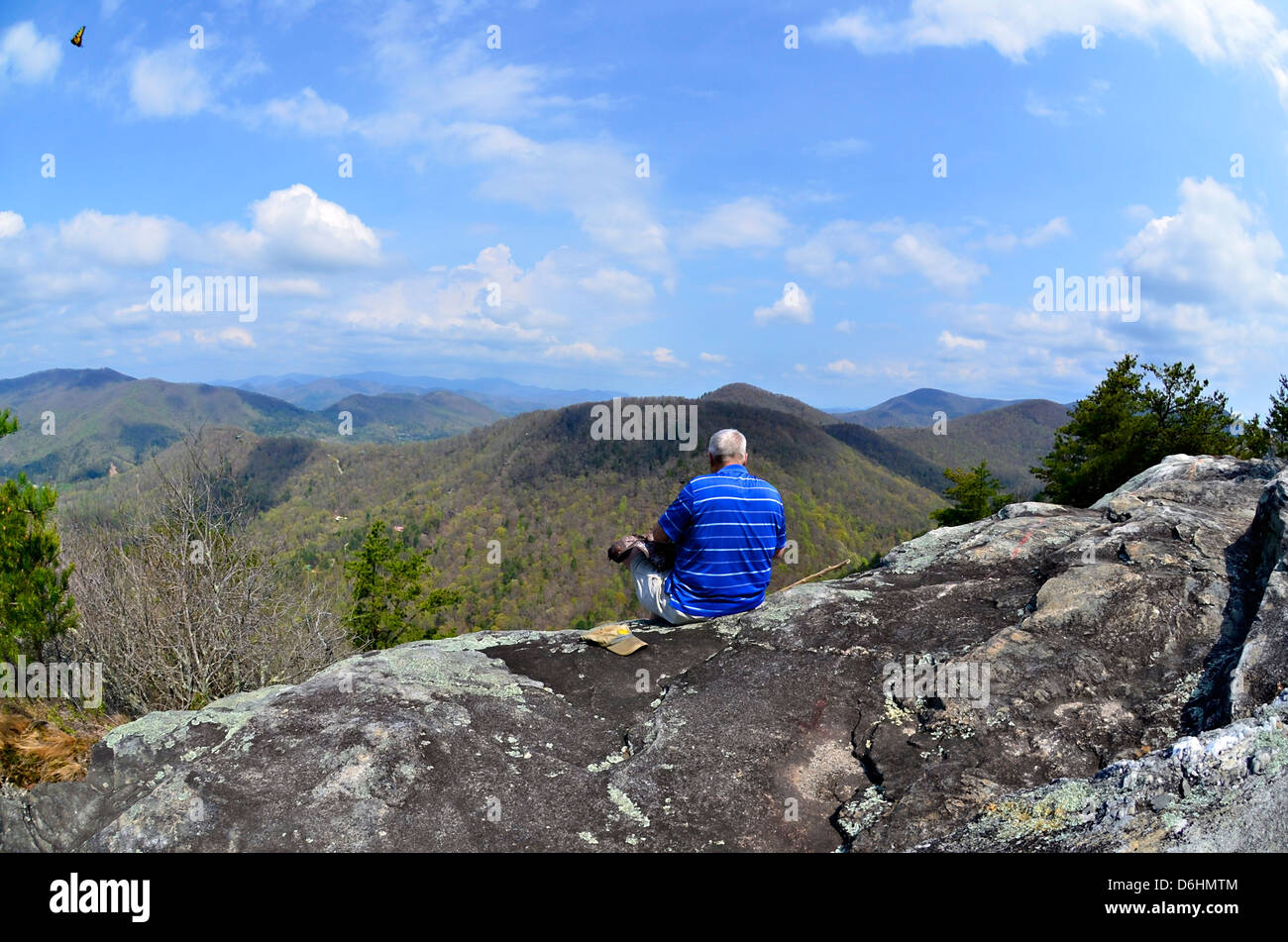 Un uomo più anziano di prendere una pausa da escursionismo per godere la vista a un si affacciano sulle montagne. Foto Stock