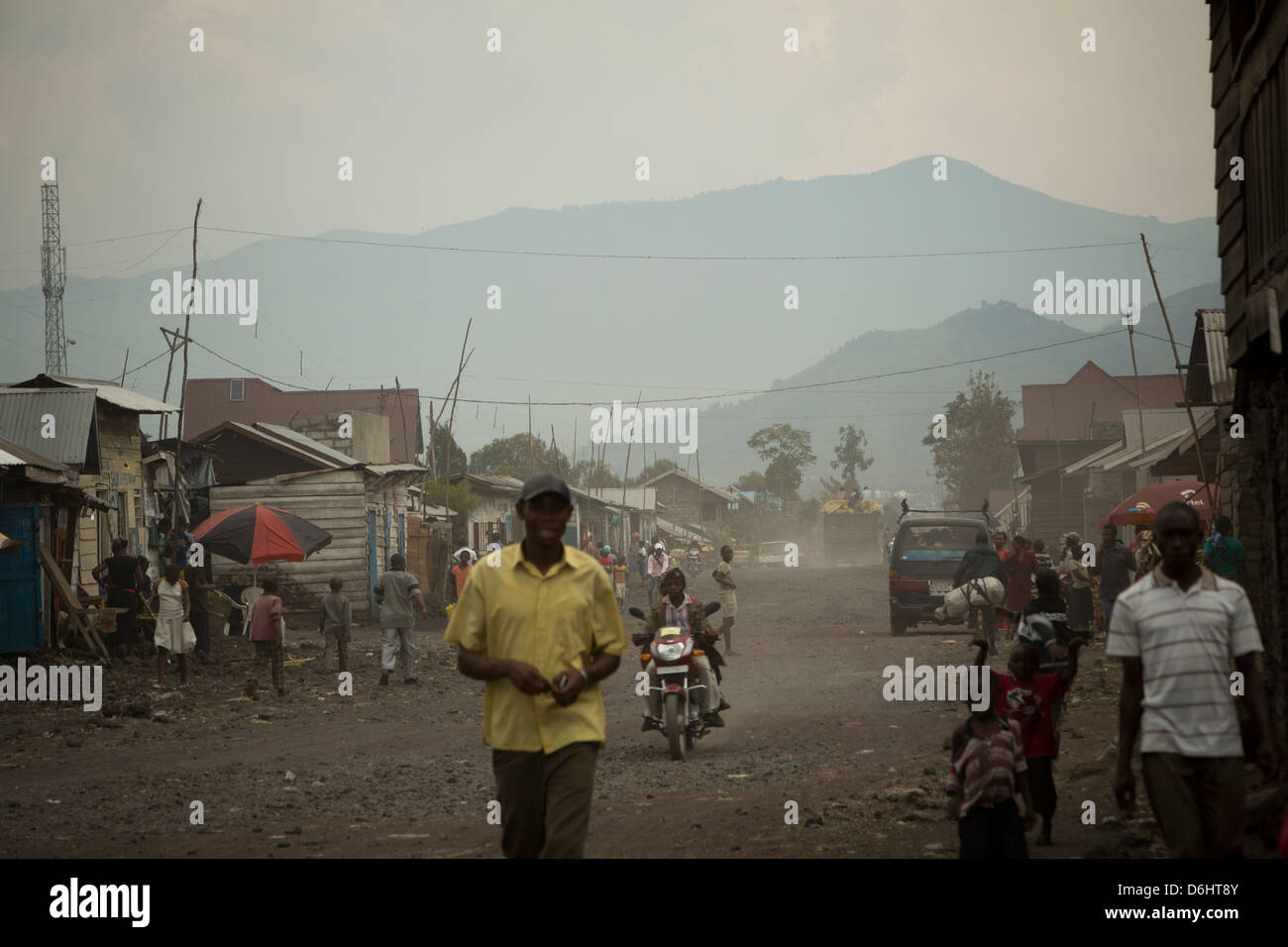 Auto e il traffico pedonale si muovono attraverso le strade polverose di Goma, nella Repubblica democratica del Congo. Foto Stock