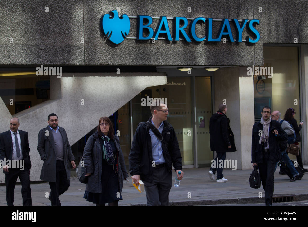 I pedoni passano davanti a una filiale della Barclays Bank nel centro di Londra durante l'ora di punta mattutina, catturando la frenetica vita urbana del quartiere finanziario della città. Foto Stock