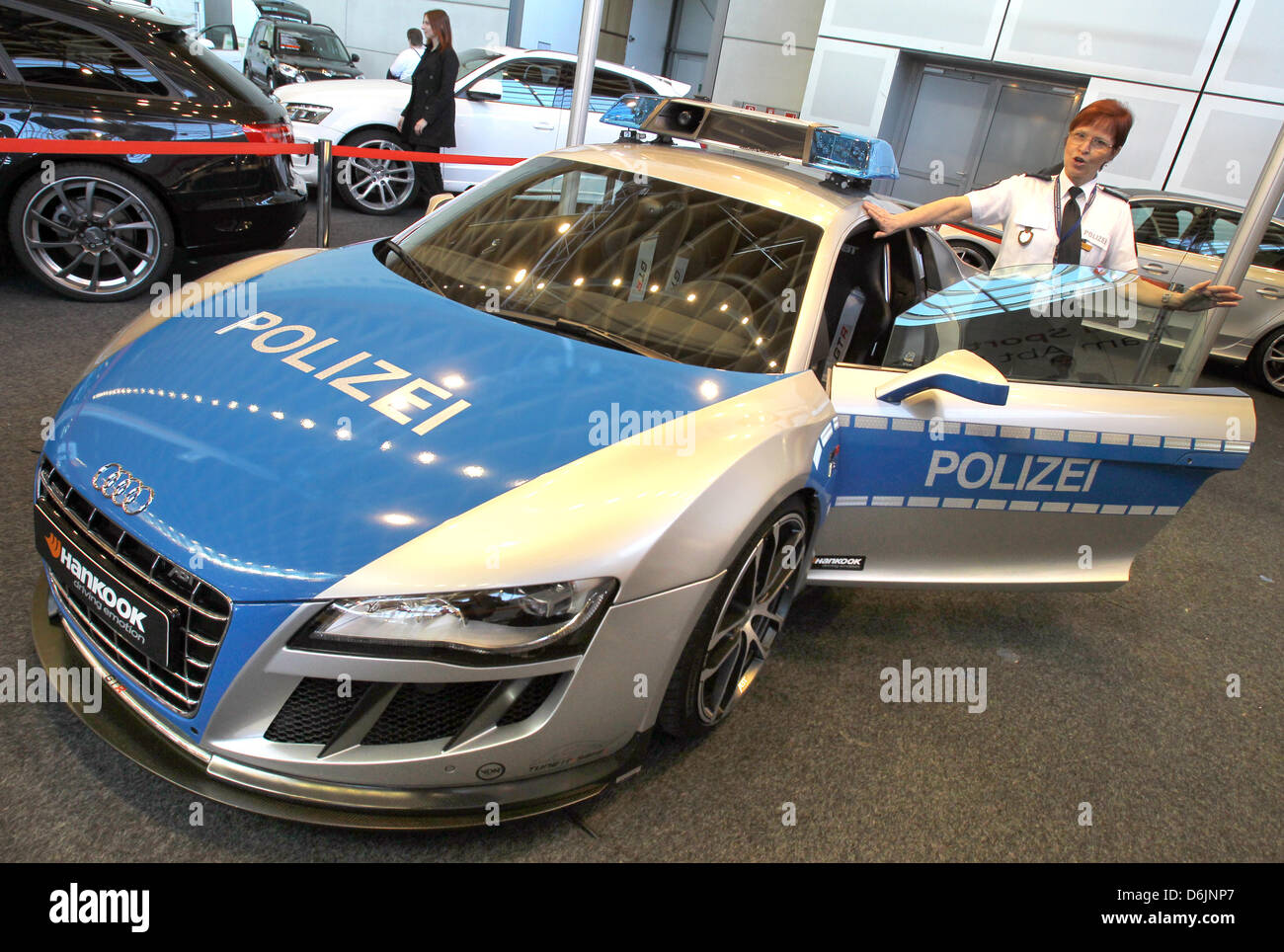 Funzionario di polizia Angelika Reichelt sorge accanto a un sintonizzato 620 PS Audi Abt R8 GTR auto della polizia presso l'automobile trade show 'Auto Trend 2012' a Rostock, Germania, 23 marzo 2012. Per ragioni commerciali, la vettura è stata attrezzata come una macchina della polizia al fine di dimostrare che sintonizzato auto può essere sicuro e consentito dalla polizia. 28 aziende e 260 diversi modelli saranno presentati fino al 25 marzo 20 Foto Stock