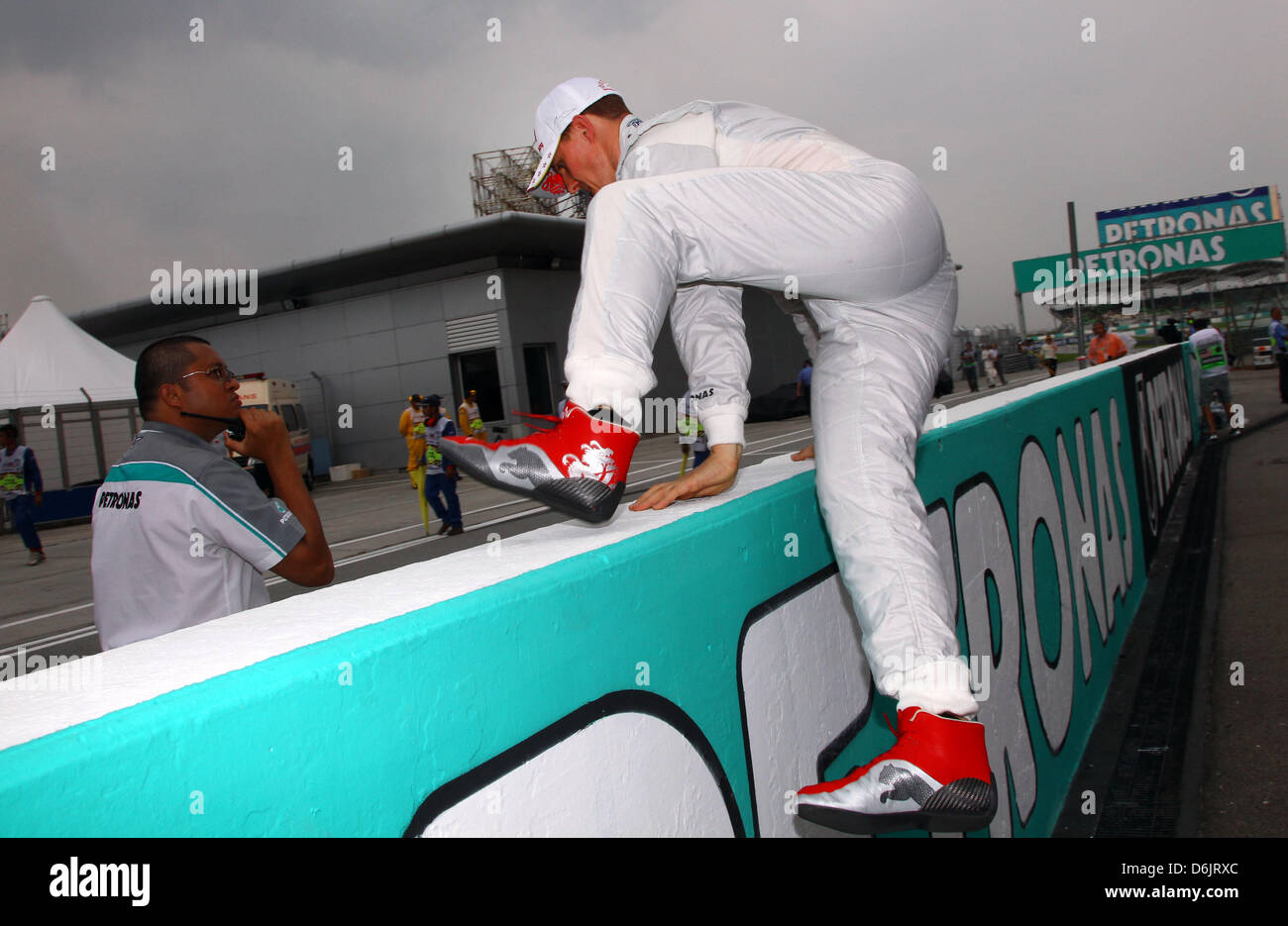 Il tedesco pilota di Formula Uno Michael Schumacher della Mercedes GP scavalca il muretto box prima di avviare il Formula One Grand Prix della Malesia sul circuito di Sepang, al di fuori di Kuala Lumpur, Malesia, 25 marzo 2012. Foto: Jens Buettner dpa Foto Stock